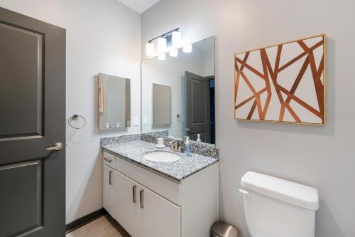 a bathroom with a sink and a toilet and a mirror at Landing Modern 3BD Gym Rooftop Lounge in Bellview