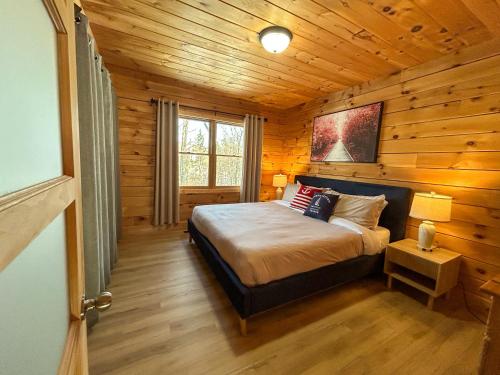 a bedroom with a bed in a log cabin at Chalet La Source Rouge in Saint-Raymond
