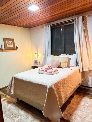 a bedroom with a large bed with a window at Chale Allegra - Hidro Aquecida - Vista para o Lago in Venda Nova do Imigrante