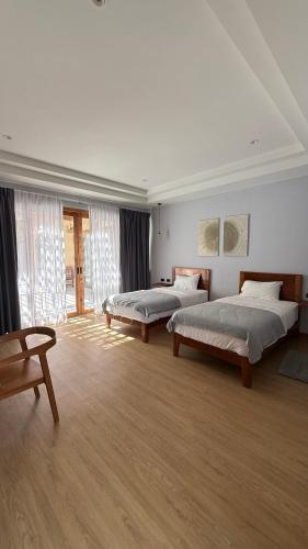 two beds in a large room with wooden floors at Private Pool Villa in Khao Lak