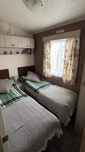 two beds in a small room with a window at WillowWay168, Tranquility Family Home in Camber