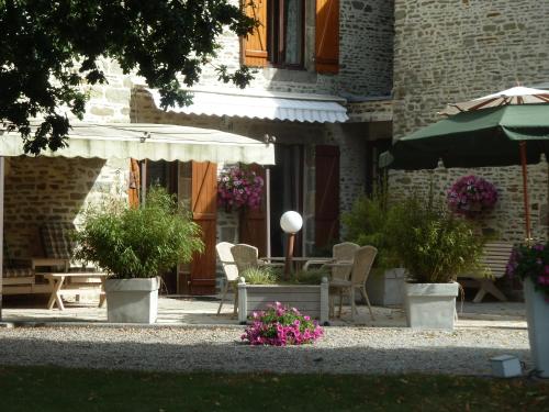 a patio with a table and chairs and an umbrella at Les Bruyères du Mont in Céaux