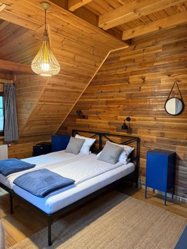 two beds in a room with wooden walls at Wypoczynek pod Lipami in Ruciane-Nida