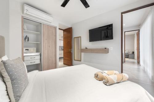 a bedroom with a white bed and a tv on the wall at Swim-up 1-bedroom apartment in Playa del Carmen