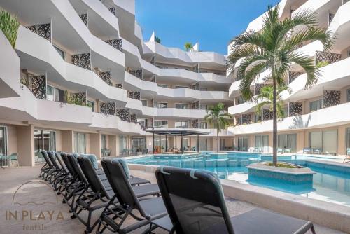 a hotel with a swimming pool and chairs in front of a building at Swim-up 1-bedroom apartment in Playa del Carmen