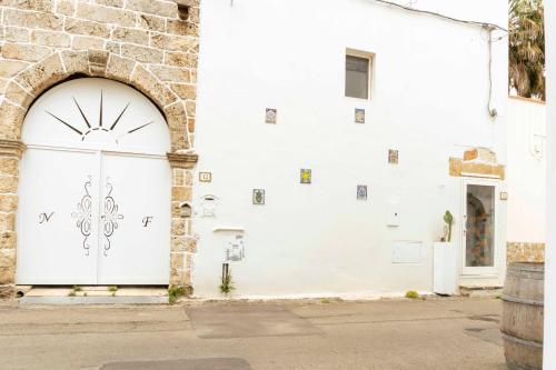 a white door on a white building with pictures on it at Zen Palazzo Storico in Alliste