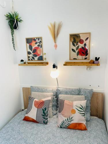 a bedroom with a bed with pillows and paintings on the wall at Les Pins Marins, Proche plages in Saint-Jean-de-Monts