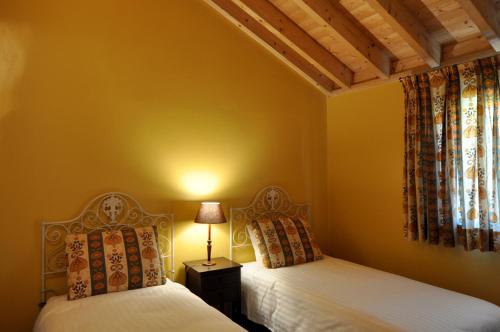 two beds in a room with yellow walls at Casa do Alto Montalegre in Montalegre