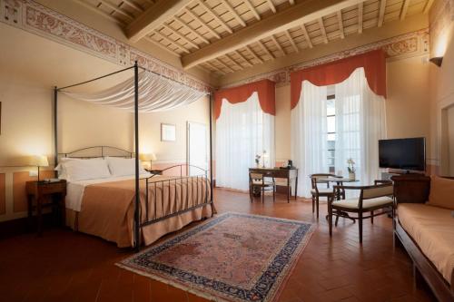 a bedroom with a bed and a tv and a couch at L'Antico Pozzo Historic Hotel in San Gimignano