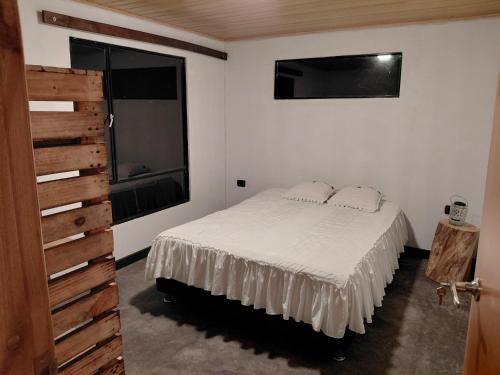 a bedroom with a white bed and a window at Refugio rural MITA in Zipacón