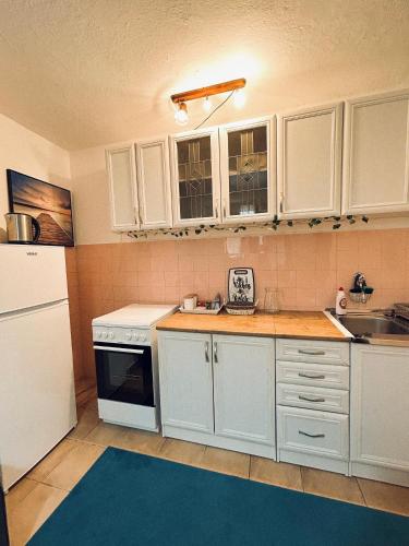 a kitchen with white cabinets and a blue rug at Blue Shell Apartments in Kotor