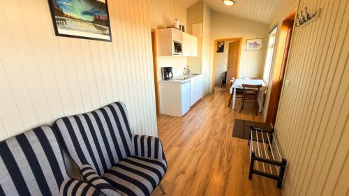 a living room with a striped couch and a kitchen at Fossatún Sunset Cottage in Fossatún