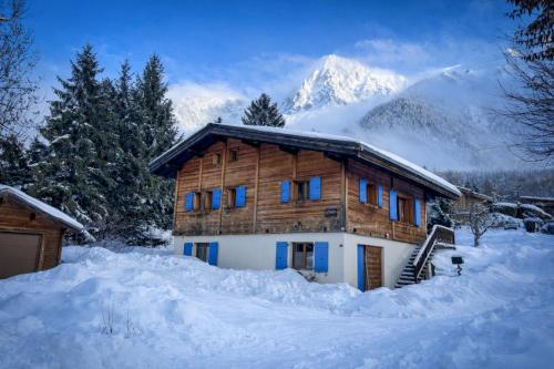 a log cabin in the snow with a mountain in the background at Chalet Les Frenes in Chamonix