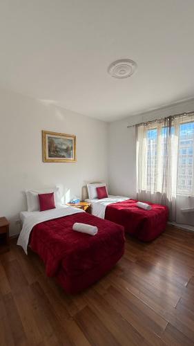 Ein Schlafzimmer mit zwei Betten, bezogen mit roter Bettwäsche und Holzboden in der Unterkunft Two Ducks in Rom