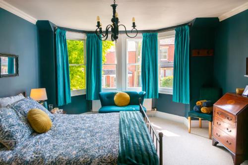 a bedroom with blue walls and a bed and a chair at Balcarres, Rodborough Avenue in Stroud