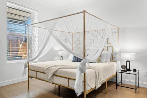 a white bedroom with a canopy bed with white sheets at Casa Ybor Apartments on 7th Ave in Tampa