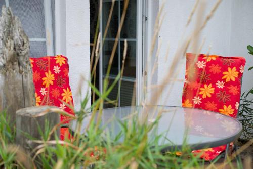 a glass table and two red pillows on a patio at Ferienhaus Kaptein Meyer in Zingst