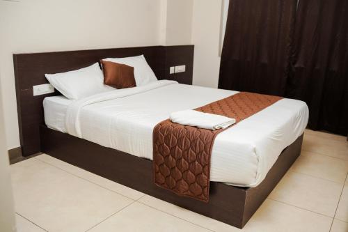 a bedroom with a large bed with brown and white sheets at krishna suites guruvayur in Guruvāyūr