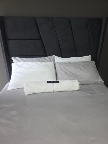 a white bed with a black headboard and white pillows at The Good Samaritan 1 in eMalahleni