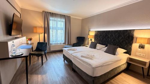 a hotel room with a large bed and a desk at Ryck-Hotel Garni in Greifswald