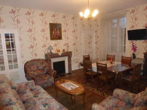 sala de estar con chimenea, mesa y sillas en Maison Commandant Blaison en Lapalisse