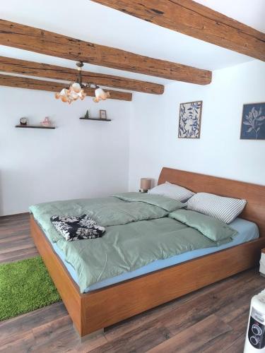 a bedroom with a large bed with green sheets at Old house by the stream in Donja Stubica