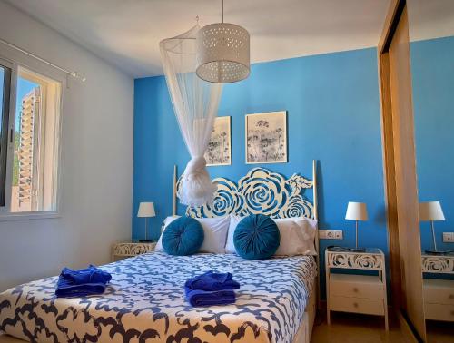 a bedroom with blue walls and a bed with blue pillows at Delfines 61 in Corralejo