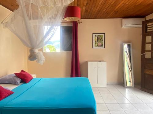 a bedroom with a blue bed and a window at Roger et Micheline a Kaz in Le Carbet