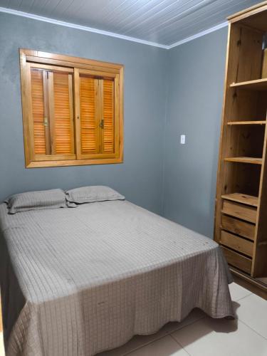 a bedroom with a bed and a wooden cabinet at Casa com dois quartos cama de casal e vista panorâmica próximo a Gramado Serra Gaúcha in Igrejinha