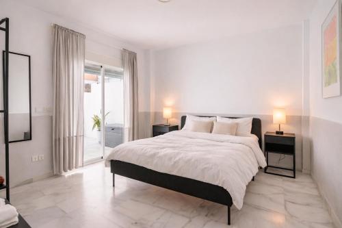 a white bedroom with a large bed with two night stands at Sofia Luxury Apartment in Seville