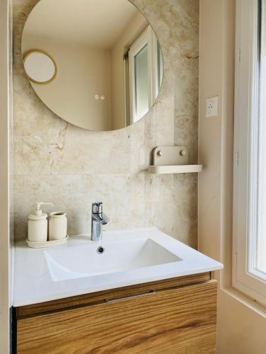 a bathroom with a white sink and a mirror at Les Bons Vivants - L'appartement in Trouville-sur-Mer
