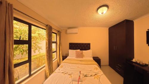 a bedroom with a bed and a large window at Kings Rest Bed And Breakfast in Gaborone
