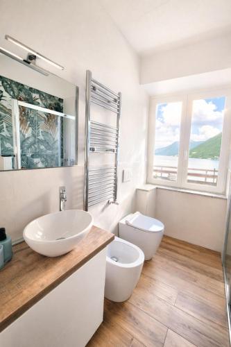 a white bathroom with a sink and a toilet at Como Lake View in Brienno