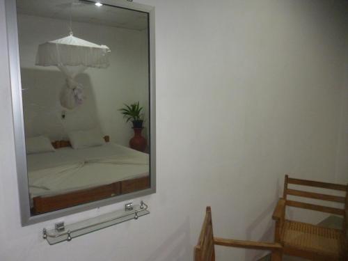 a mirror on a wall with a bed in a room at Sigiri Lodge in Sigiriya
