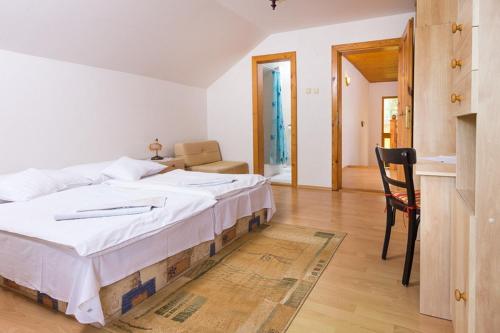 a bedroom with a large white bed and a chair at Vila Kantor in Vyšné Hágy