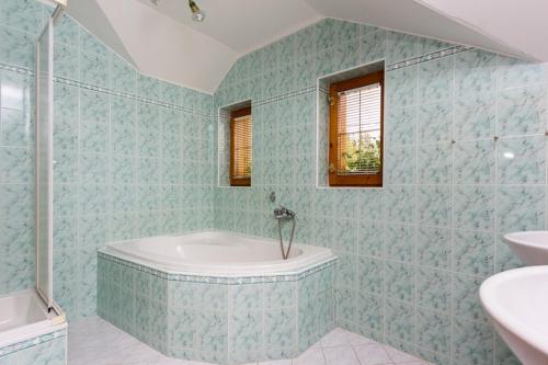a blue tiled bathroom with a tub and a sink at Vila Kantor in Vyšné Hágy