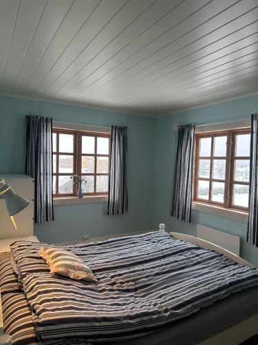 a large bed in a room with two windows at Familievennlig fritidsbolig i hjertet av Flå, perfekt for besøk i Bjørneparken in Flå