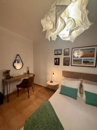 a bedroom with a bed and a desk and a chandelier at Casa D' Oliveira in Castro Verde