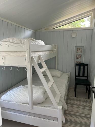 a bedroom with two bunk beds and a chair at Peaceful seaside cabin with guest house - large private outdoor areas and boat available on request in Eigebrekk
