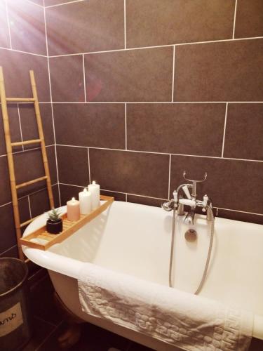 a bath tub with a faucet in a bathroom at Murmure de Tilleul in Alembon