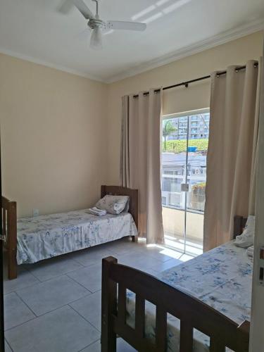 a bedroom with two beds and a large window at Apartamento da Adriana in Itajubá