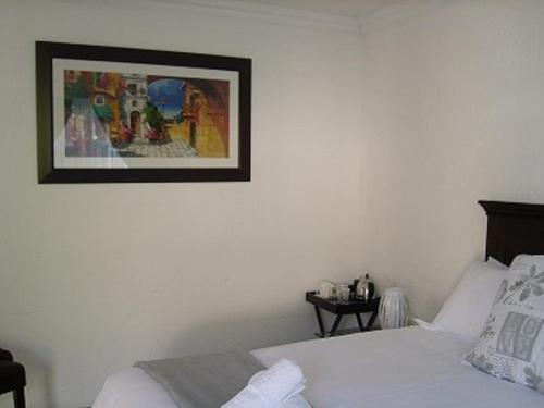 a bedroom with a bed and a picture on the wall at La Coscello Guest House in Edenvale