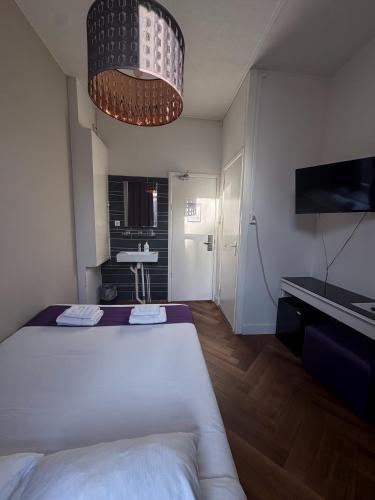 a bedroom with a large white bed and a chandelier at Hotel Bellington in Amsterdam