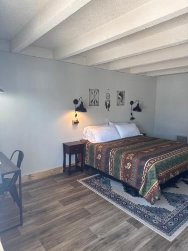 a bedroom with a bed with a table and lamps at Tecumseh Inn & Suites in Tecumseh
