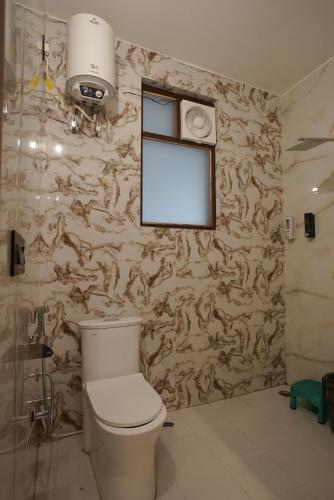 a bathroom with a toilet and a window and a wall at Corbett Valley View in Tota Ām