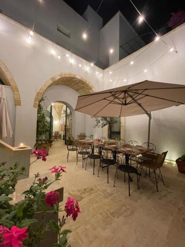 a group of tables and chairs with a large umbrella at Palazzo Flora in Collepasso