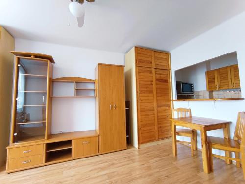 a kitchen with wooden cabinets and a table and a dining room at Garzónka Trenčín in Trenčín