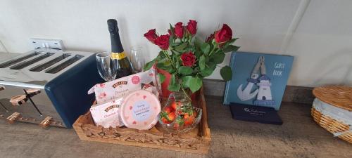 a table with a vase of roses and wine glasses at Blue Lagoon Holiday ,Bude 79 in Cubert