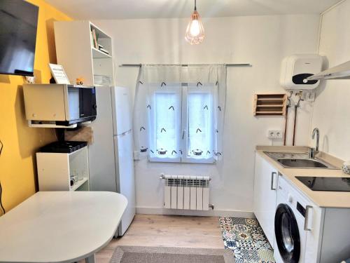 a small kitchen with a white refrigerator and a sink at Acogedor apartamento de 2 habitaciones, parking & conford in El Astillero