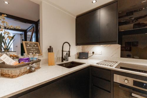 a kitchen with black cabinets and a sink at SPINDLE COTTAGE - Riverside cottage on the edge of the Peak District in Holmfirth